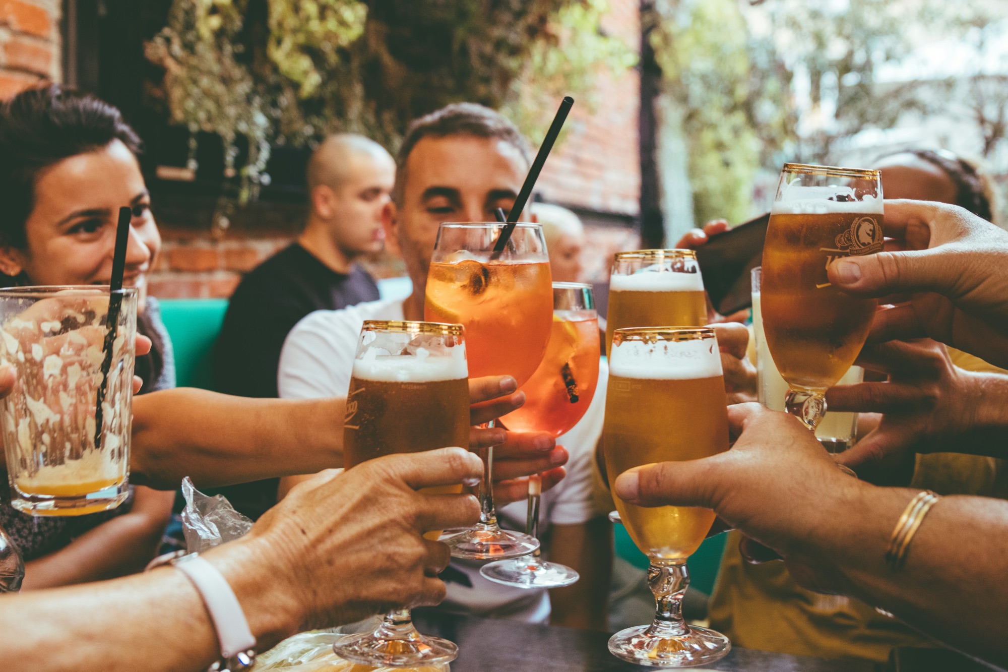 A table of guests mid-toast outdoors, drinks in hand, nobody waiting.